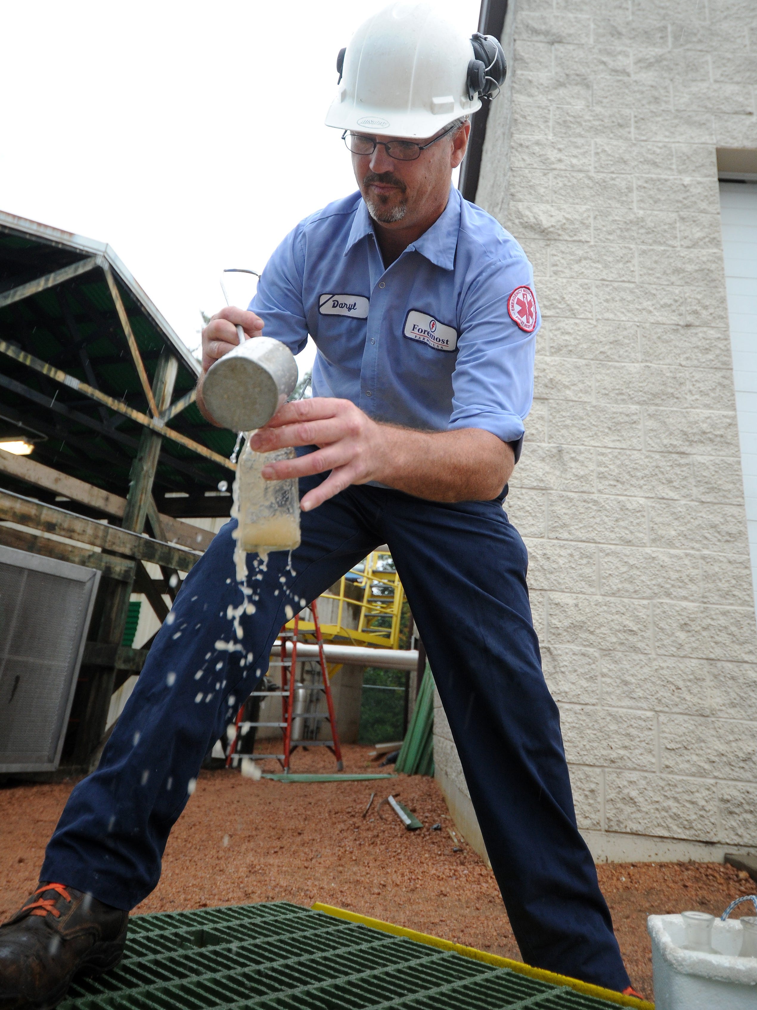 A waste treatment operator scoops up a sample to be tested at Foremost Farms in 2011.