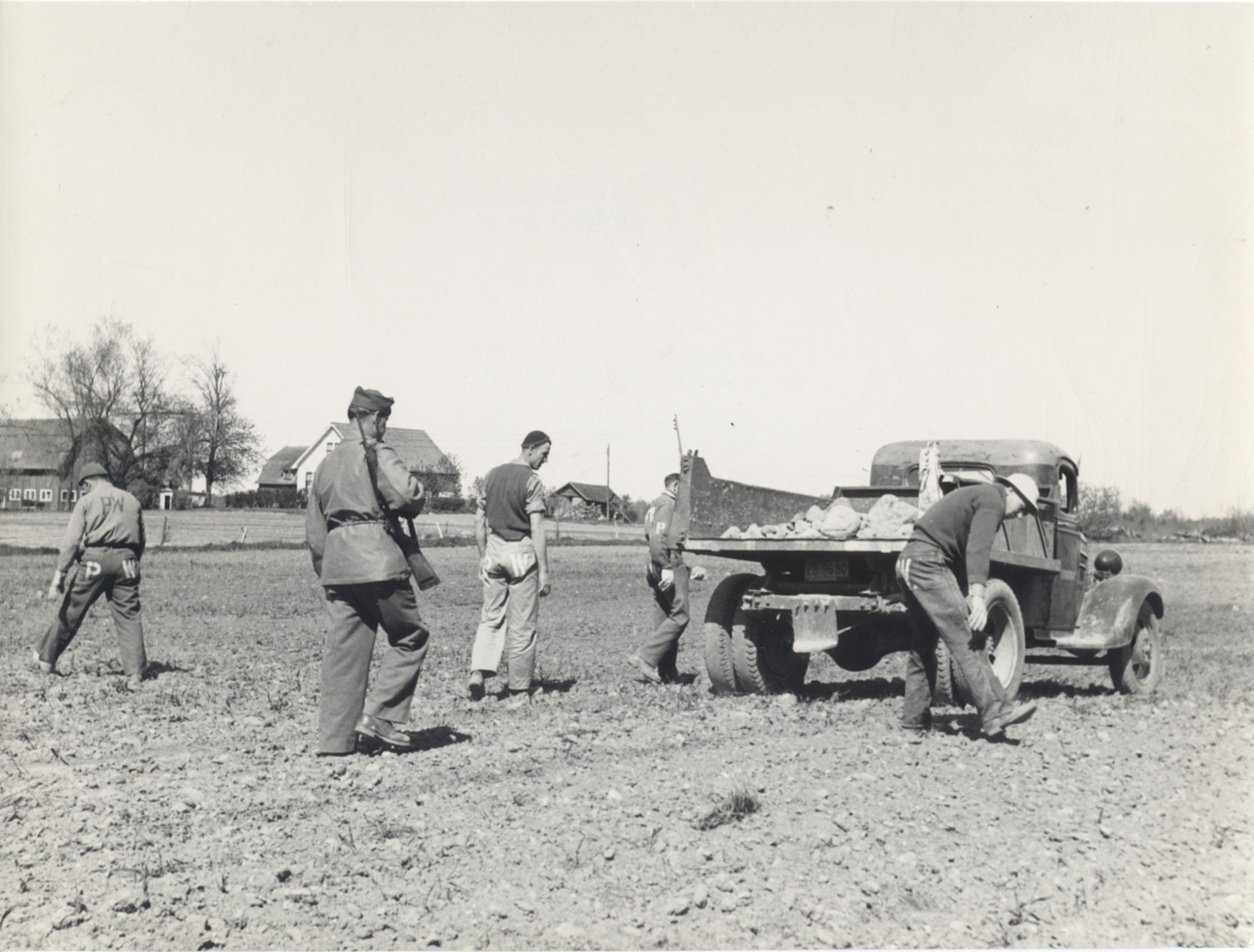 German POWs pick stones from a field in Door County, accompanied by a guard during World War II.